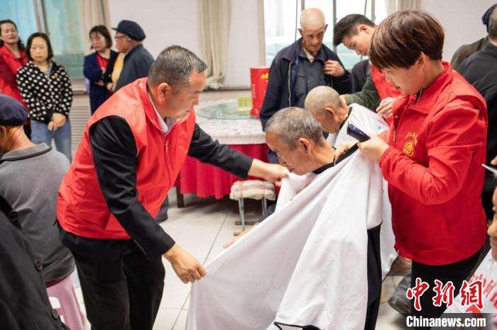 图为何军带领公司组建的爱心理发队为困难老人理发。(资料图) 岳婧婧 摄