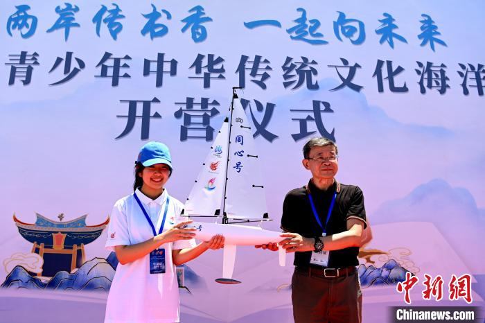 国台办交流局局长黄文涛(右)向台湾籍学员团队赠送“同心号”帆船模型。　张金川 摄